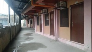 A corridor with air conditioning units mounted on the ceiling, doors with windows, and a wet floor.