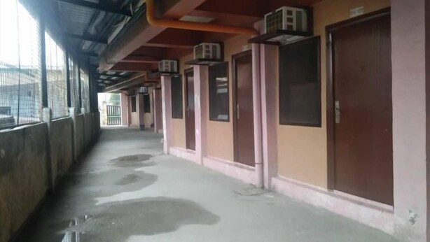 Un pasillo con unidades de aire acondicionado instaladas en el techo, puertas con ventanas y suelo mojado.