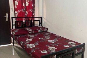 A small bed with a floral bedspread, a black metal frame, and a red curtain partially drawn. - Hotel De Amado by RedDoorz (Dagupan)