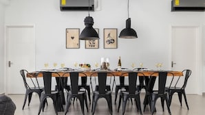 Un comedor con mesa de madera, sillas negras y lámparas colgantes.