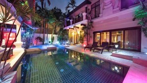 A swimming pool with a tiled floor, surrounded by lounge chairs and palm trees. - Luxurious Pattaya Pool Villa (Sattahip)