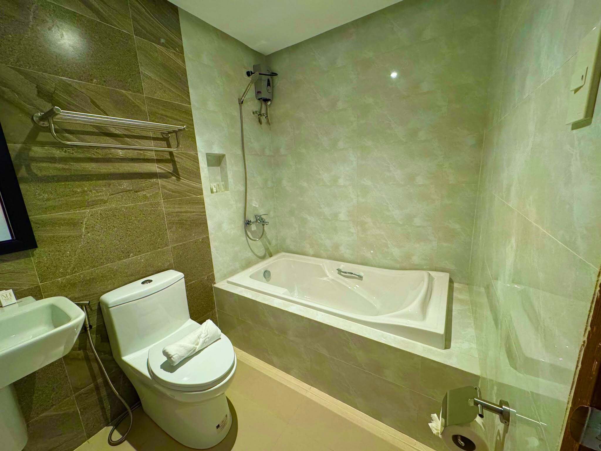 A modern bathroom with a toilet, bidet, and a freestanding bathtub.