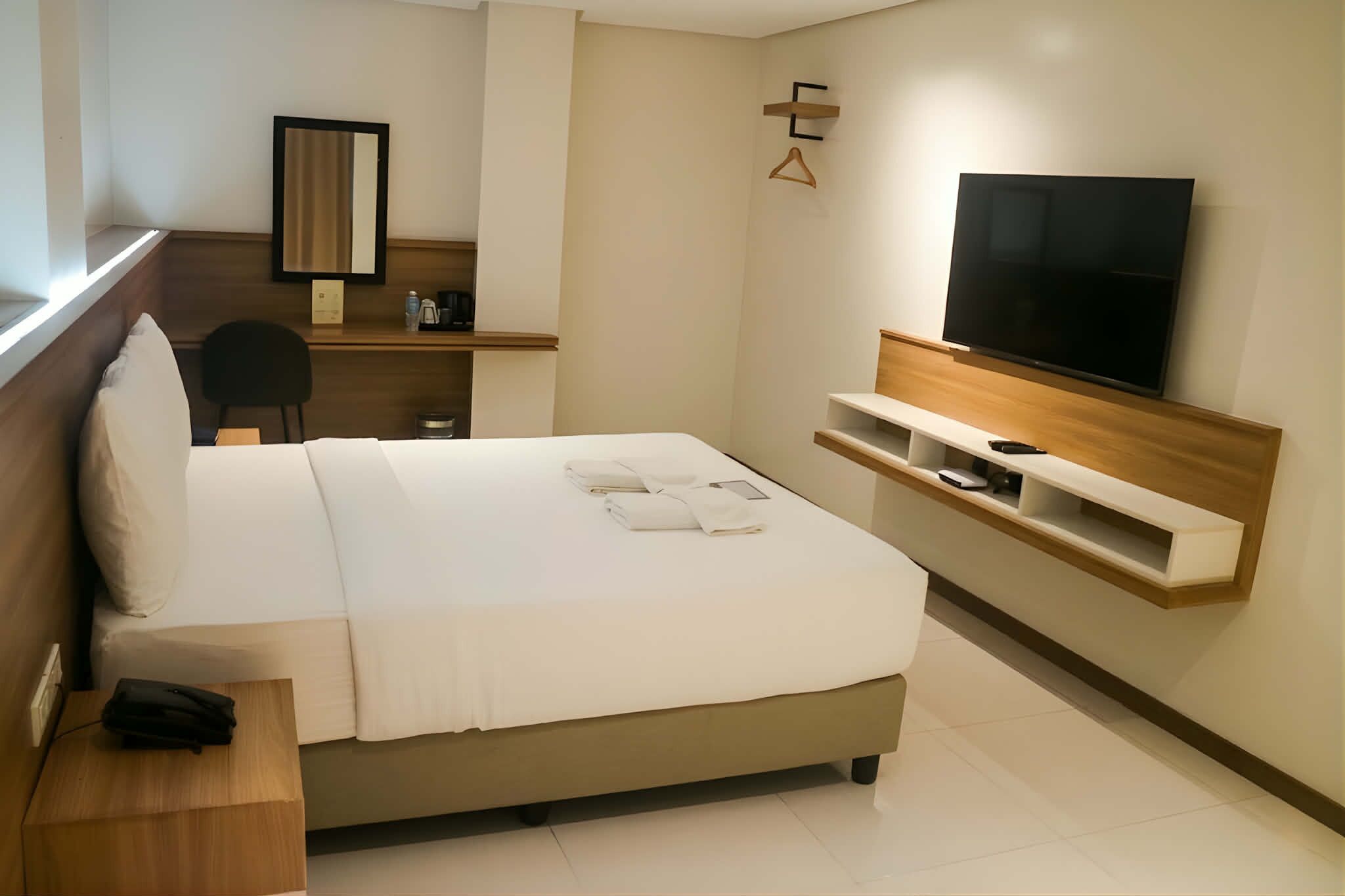 Una habitación de hotel con cama, televisión, escritorio y silla.