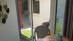 A room with a dining table, wicker chairs, a glass door leading outside, and a wall-mounted decoration. - QUIET COMFY PRIVATE TINY HOME (Caboolture)
