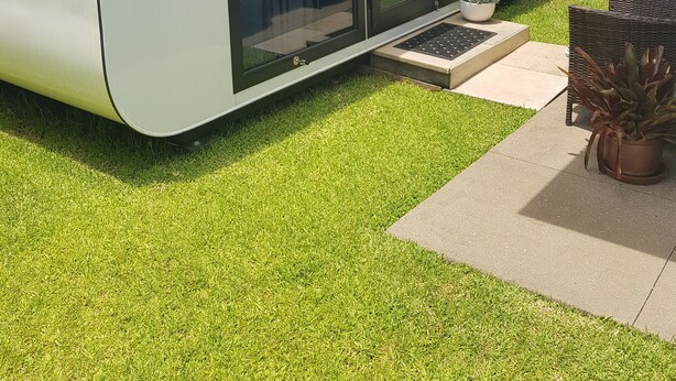 A modern house with a large sliding glass door leading to a patio area. - QUIET COMFY PRIVATE TINY HOME (Caboolture)