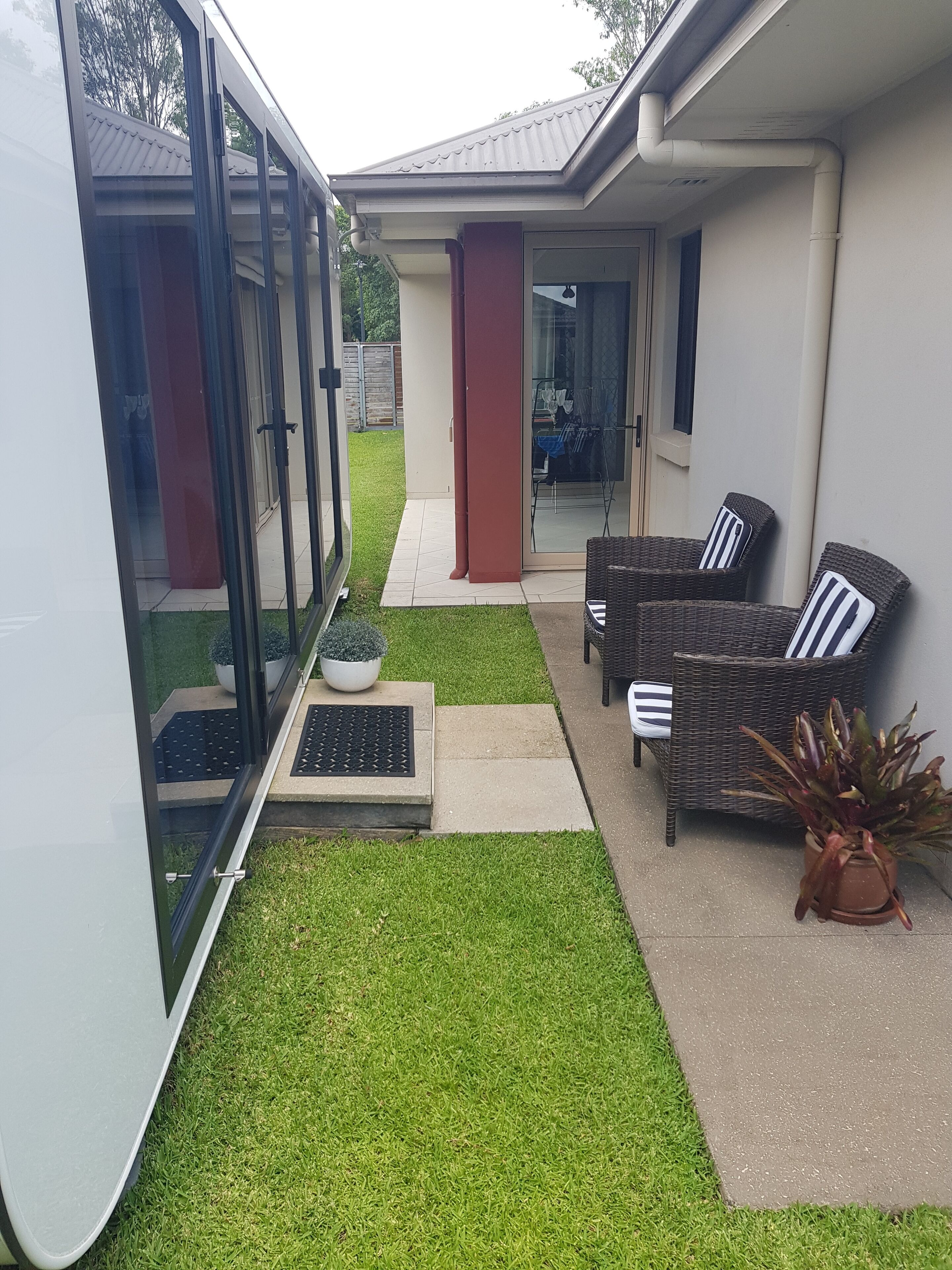 A covered patio area with a seating arrangement, a small garden, and a sliding glass door leading to a garage.