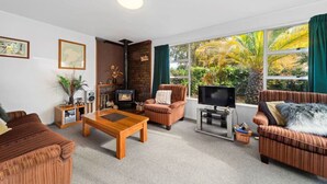 A living room with a fireplace, a television, and large windows with curtains. - Westhall in Kinloch Taupo (Kinloch)