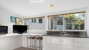 A modern kitchen with white cabinets, a built-in stove, a sink, and a large window with a view of the outdoors. - Westhall in Kinloch Taupo (Kinloch)