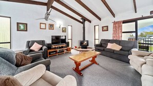 A spacious living room with a fireplace, sofas, a coffee table, and a television.