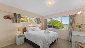 A bedroom with a large bed, bedside tables, a dresser, and a view of the outdoors. - Kinloch Lakefront with wifi (Kinloch)