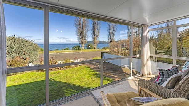 A sunlit room with large windows overlooking a grassy area and a body of water. - Kinloch Lakefront with wifi (Kinloch)