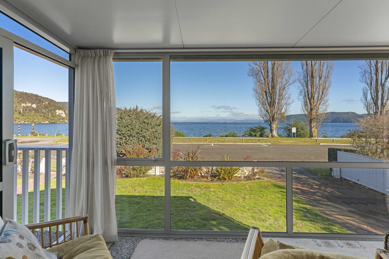 A room with a large window overlooking a grassy area and a body of water.