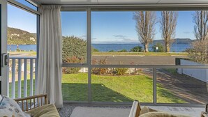 A room with a large window overlooking a grassy area and a body of water. - Kinloch Lakefront with wifi (Kinloch)