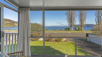 A room with a large window overlooking a grassy area and a body of water.