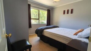 A bedroom with a bed, a window, a door, and a small desk. - Peaceful on Par Kinloch (Kinloch)