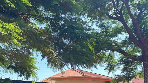 Un edificio con tetto rosso, cancello nero e un pannello decorativo a parete.