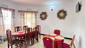 Un'area pranzo con un tavolo apparecchiato per sei persone, circondato da sedie in legno e una tovaglia rossa.