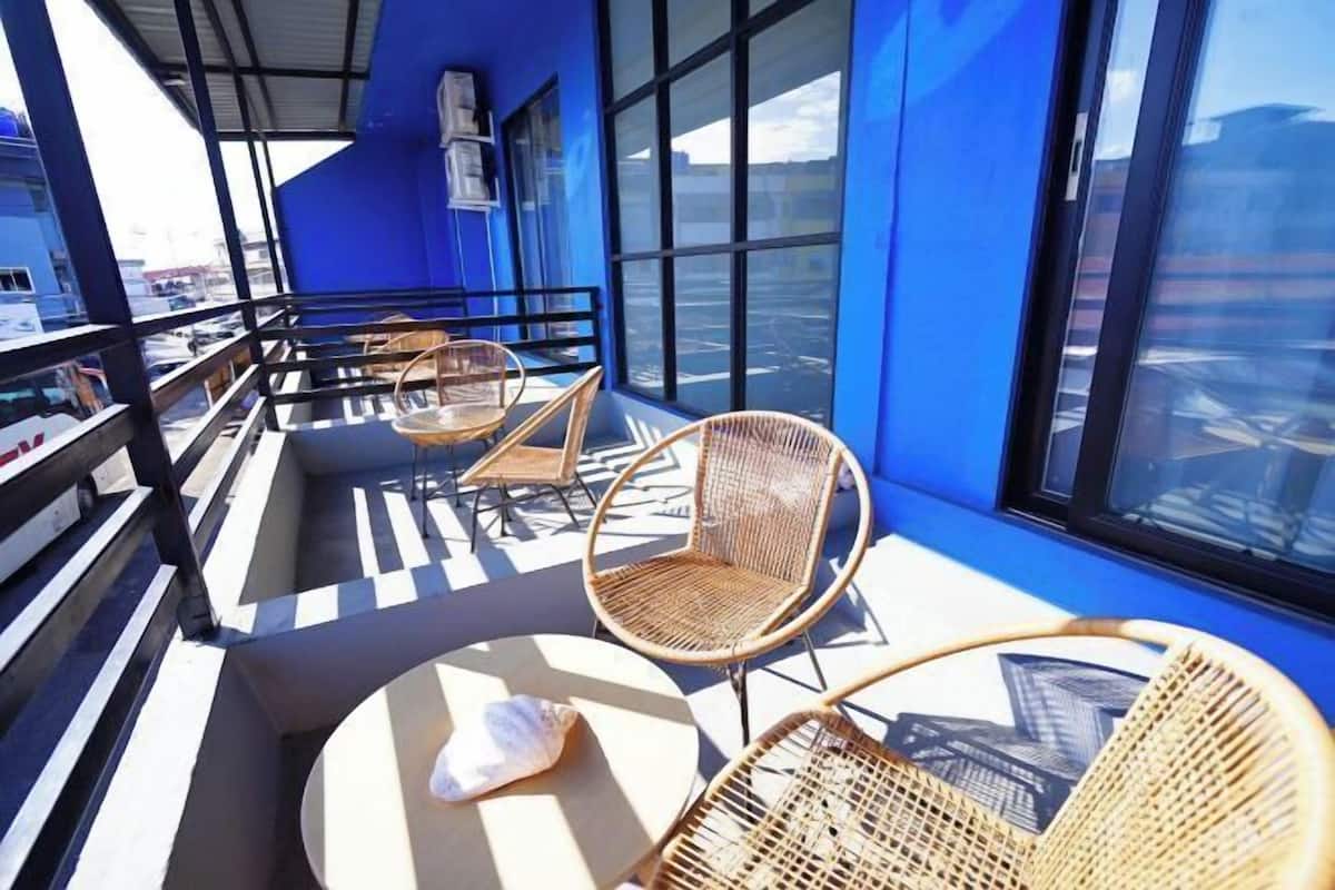 A rooftop terrace with wicker chairs, a round table, and a view of the cityscape.