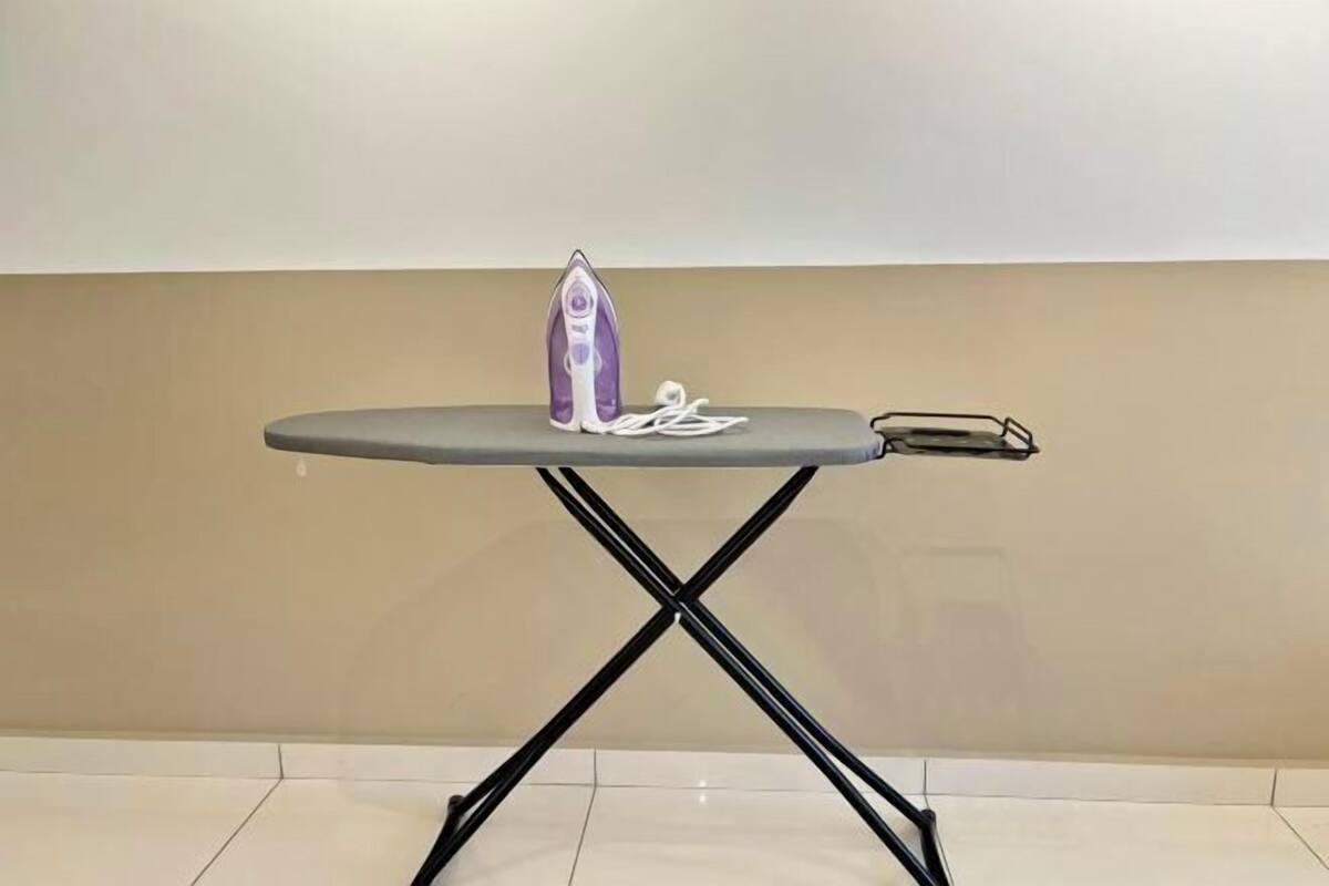 A small, round table with a purple iron and a pair of white earphones on it.