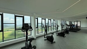 A spacious gym with various exercise equipment, large windows offering a view of the outdoors, and a modern architectural design. - Ipoh Town Horizon Skypool Suites 4-11pax by IWH Suites (Ipoh)