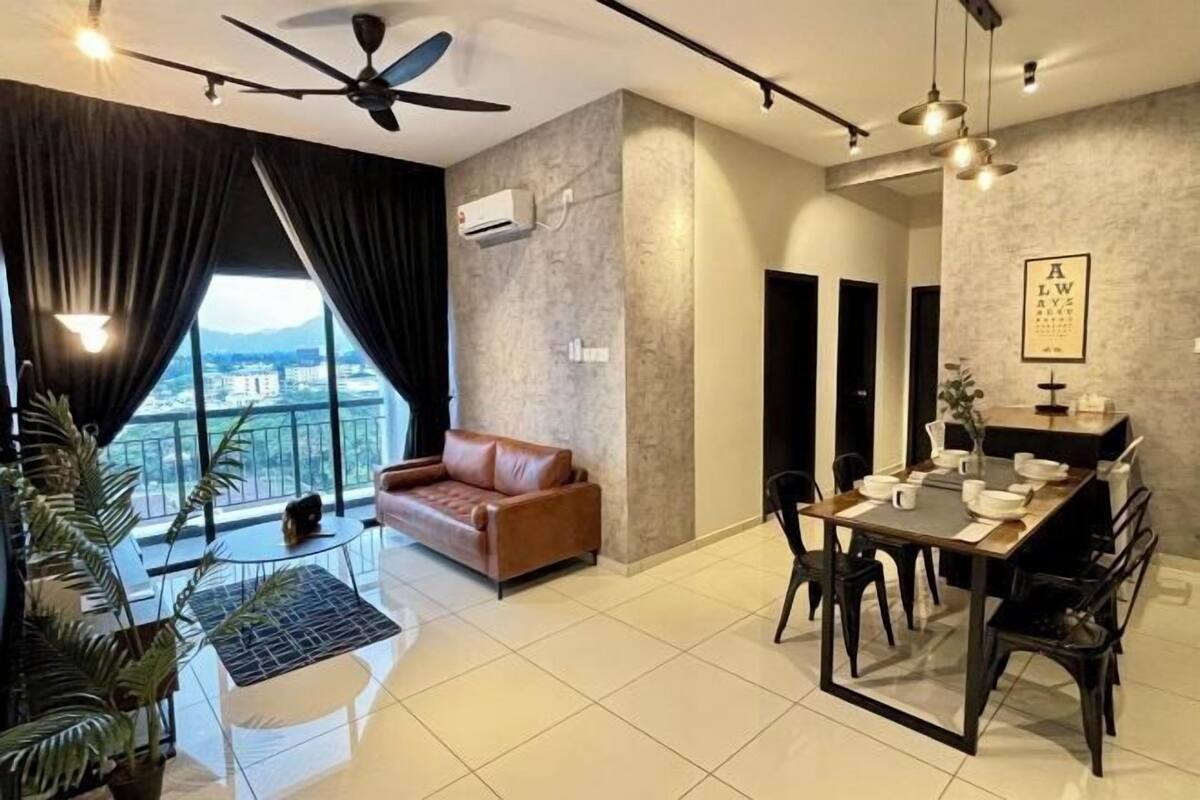 A modern living room with a brown leather sofa, a dining table with chairs, a ceiling fan, and a large window with curtains.