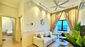A modern living room with a sofa, a round table, and a large window with curtains. - Ipoh Town Horizon Skypool Suites 4-11pax by IWH Suites (Ipoh)