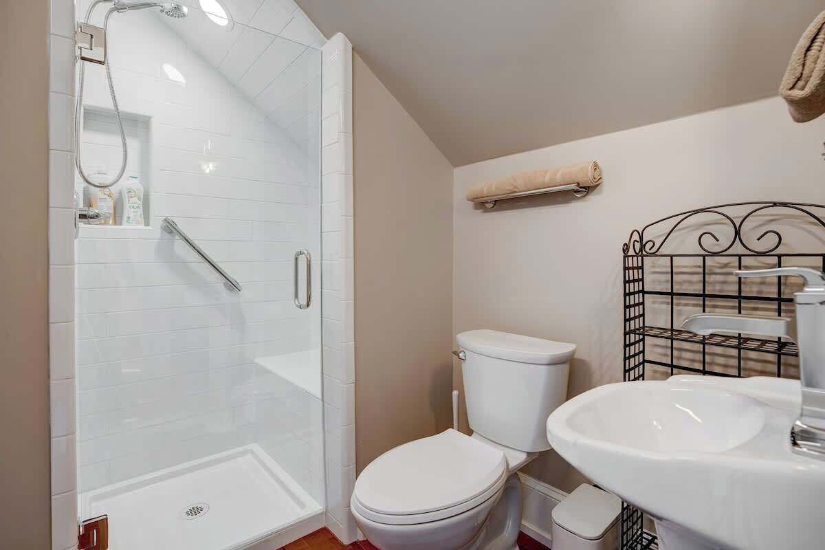 Une salle de bain avec une douche à parois de verre, des toilettes blanches et un lavabo blanc.