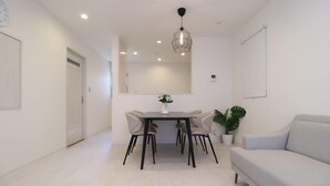 A modern living room with a dining table, sofa, and a hanging light fixture. - Andnext Holiday House (Kyoto)