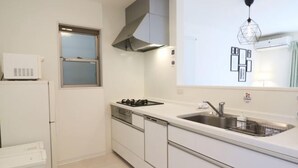 A modern kitchen with white cabinets, a built-in stove, a sink, and a window. - Andnext Holiday House (Kyoto)