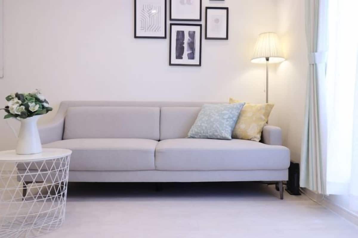 Ein modernes Wohnzimmer mit einer Couch, einem Beistelltisch mit einer Vase und einer Stehlampe.