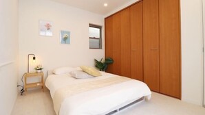A bedroom with a bed, bedside table, lamp, and a wardrobe. - Andnext Holiday House (Kyoto)