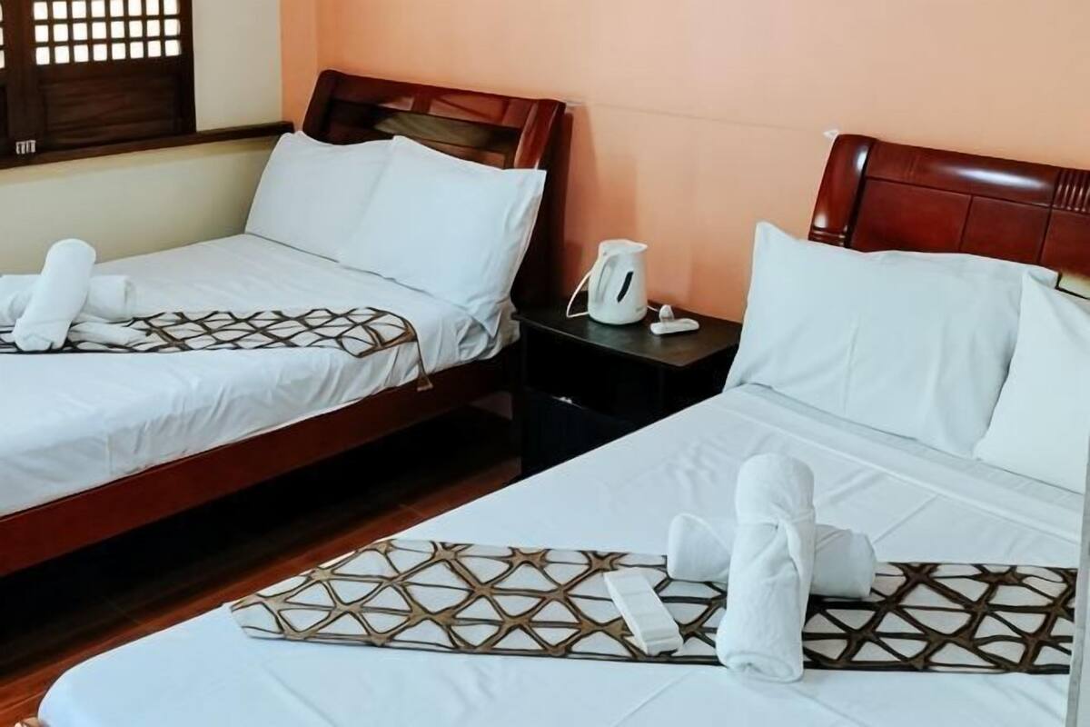 Two twin beds with wooden headboards, white bedding, and towels.