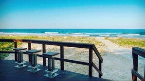 Una terraza de madera con bancos que da a una playa.