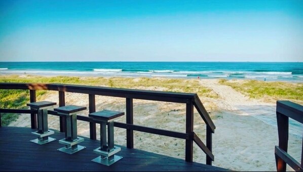 A wooden deck with benches overlooking a beach.