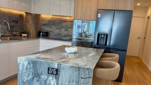Una cocina moderna con una isla de mármol, electrodomésticos de acero inoxidable y armarios de madera.