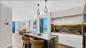 Una cocina moderna con una isla de mármol, taburetes de bar y un salpicadero de piedra.