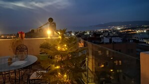 A balcony with a table and chairs, a potted plant, and a Christmas tree with lights. - Paradise House Apartment in Tamraght (Tamraght)