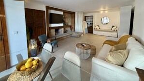 Una sala de estar moderna con un sofá, sillas, una mesa de centro y un televisor montado en la pared.