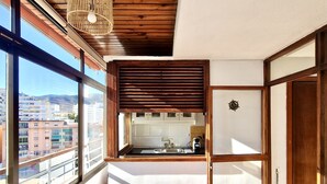 Una cocina compacta con vistas a la ciudad, techo de madera y una lámpara colgante.