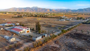 Vista aérea de una zona rural con un pequeño conjunto de edificios, incluyendo una estructura de techo rojo y un edificio blanco con garaje.