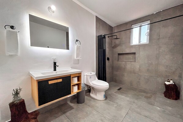 A modern bathroom with a large mirror, white sink, and toilet.