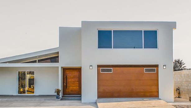 Una casa moderna de dos pisos con garaje, ventanas amplias y techo plano.