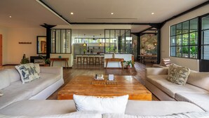 A modern living room with a wooden coffee table, two sofas, and a kitchen in the background. - Bon Ton Villa By Betterplace (Canggu)