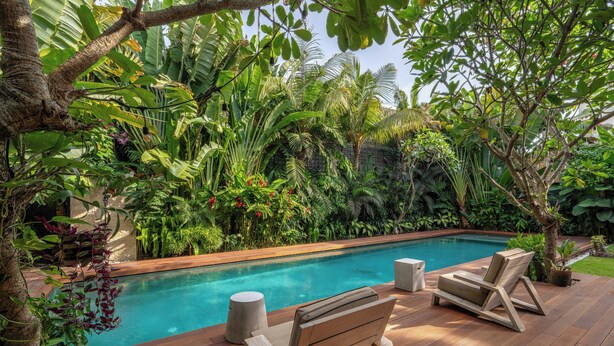 A wooden deck with a pool, surrounded by lush tropical plants and trees. - Bon Ton Villa By Betterplace (Canggu)