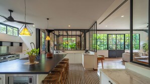 A modern kitchen with a central island, bar stools, and a built-in microwave. - Bon Ton Villa By Betterplace (Canggu)