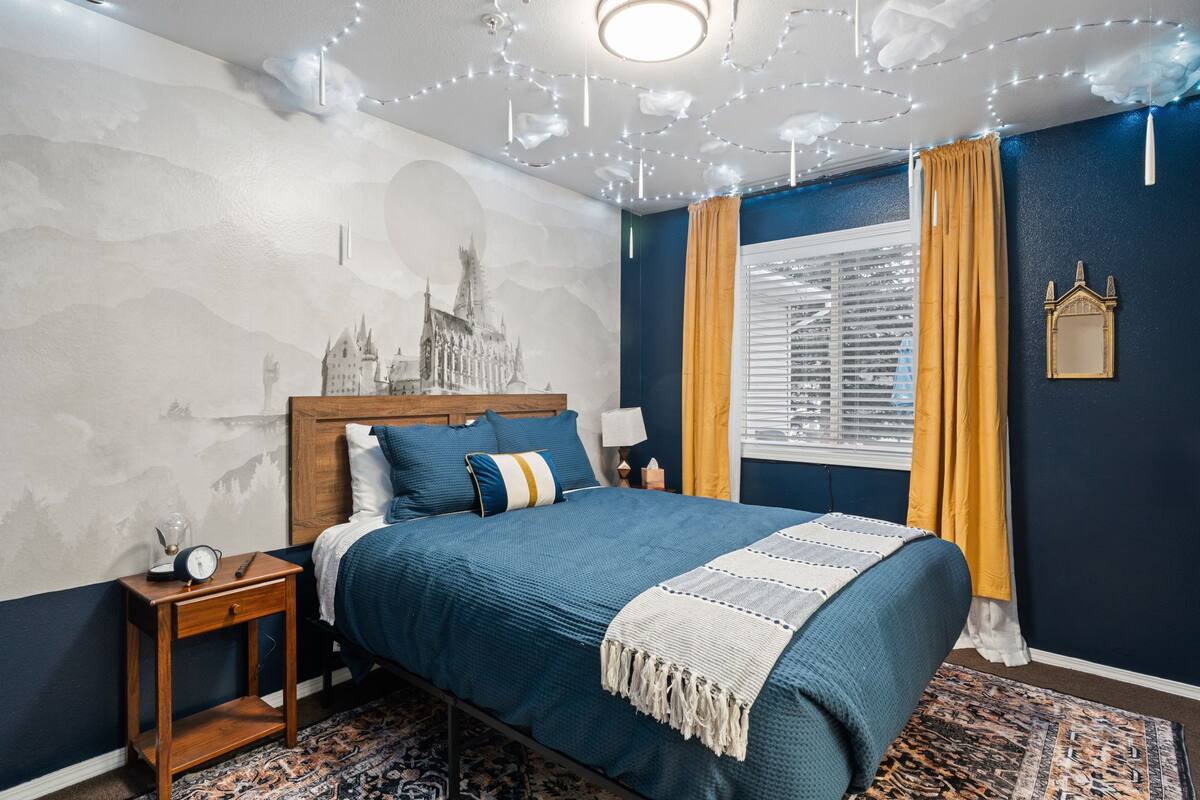 A bedroom with a bed, nightstand, and a wall mural.