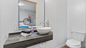 A bathroom with a white sink, a mirror, a toilet, and a wooden countertop. - Library INN LLC (Lava Hot Springs)