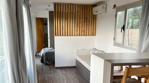 Une chambre moderne avec un plancher en bois, un lit, un bureau et une fenêtre avec des rideaux.