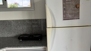 Une cuisine de taille réduite, avec un réfrigérateur blanc, un four à micro-ondes et un petit plan de travail.