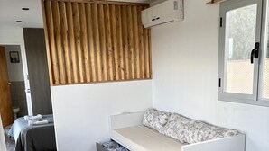Une chambre compacte et moderne, dotée d’un lit intégré, d’un panneau mural en lattes de bois et d’une fenêtre offrant une vue agréable.